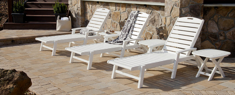 White Trex Outdoor Furniture Yacht Club 3-Piece Chaise Sets sit on a brick patio by a stone house.