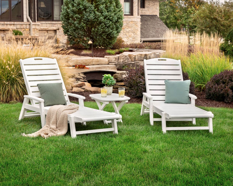 A white Trex Outdoor Furniture Yacht Club 3 Piece Chaise Set sits on a lawn before a brick house with landscaping.